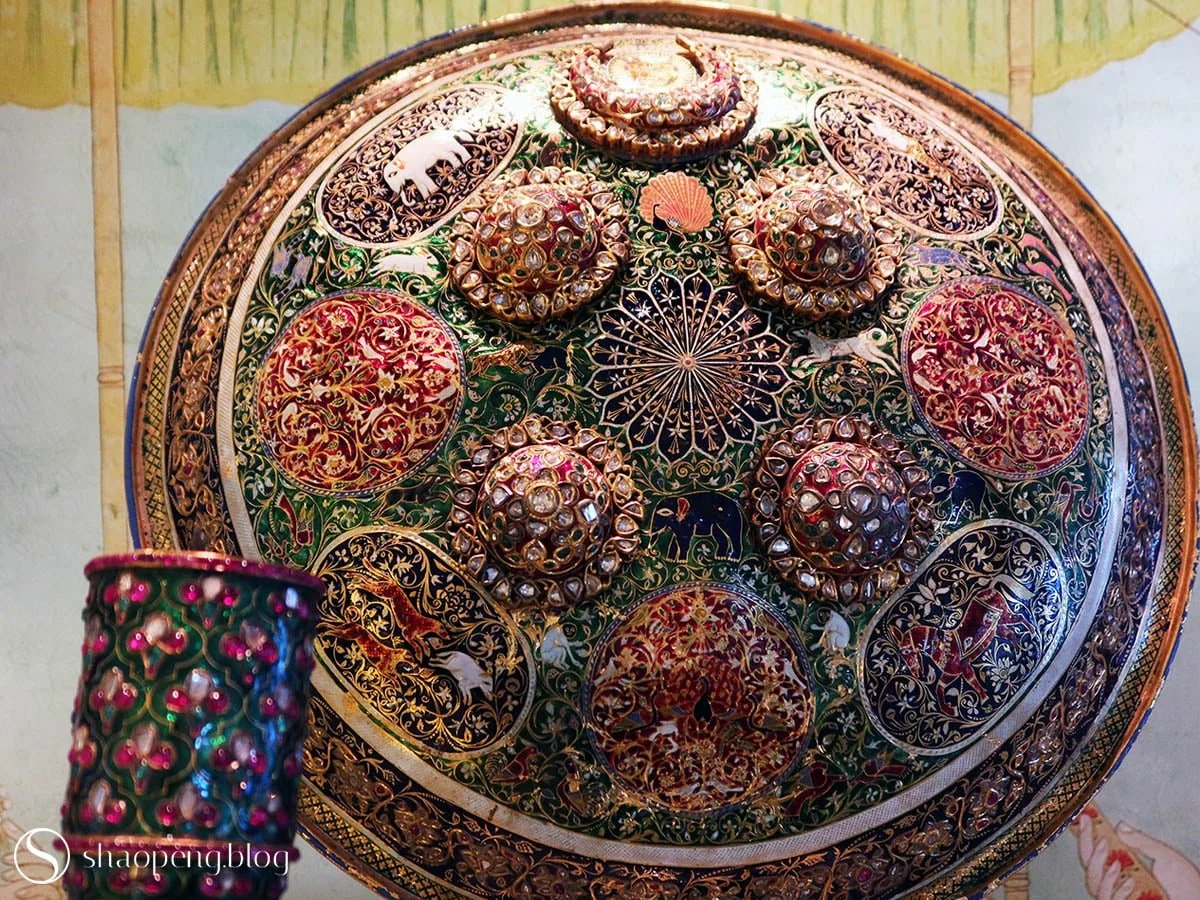 From 19th-century Jaipur, this gold shield dazzles with lavish gemstones and intricate enamel work.
