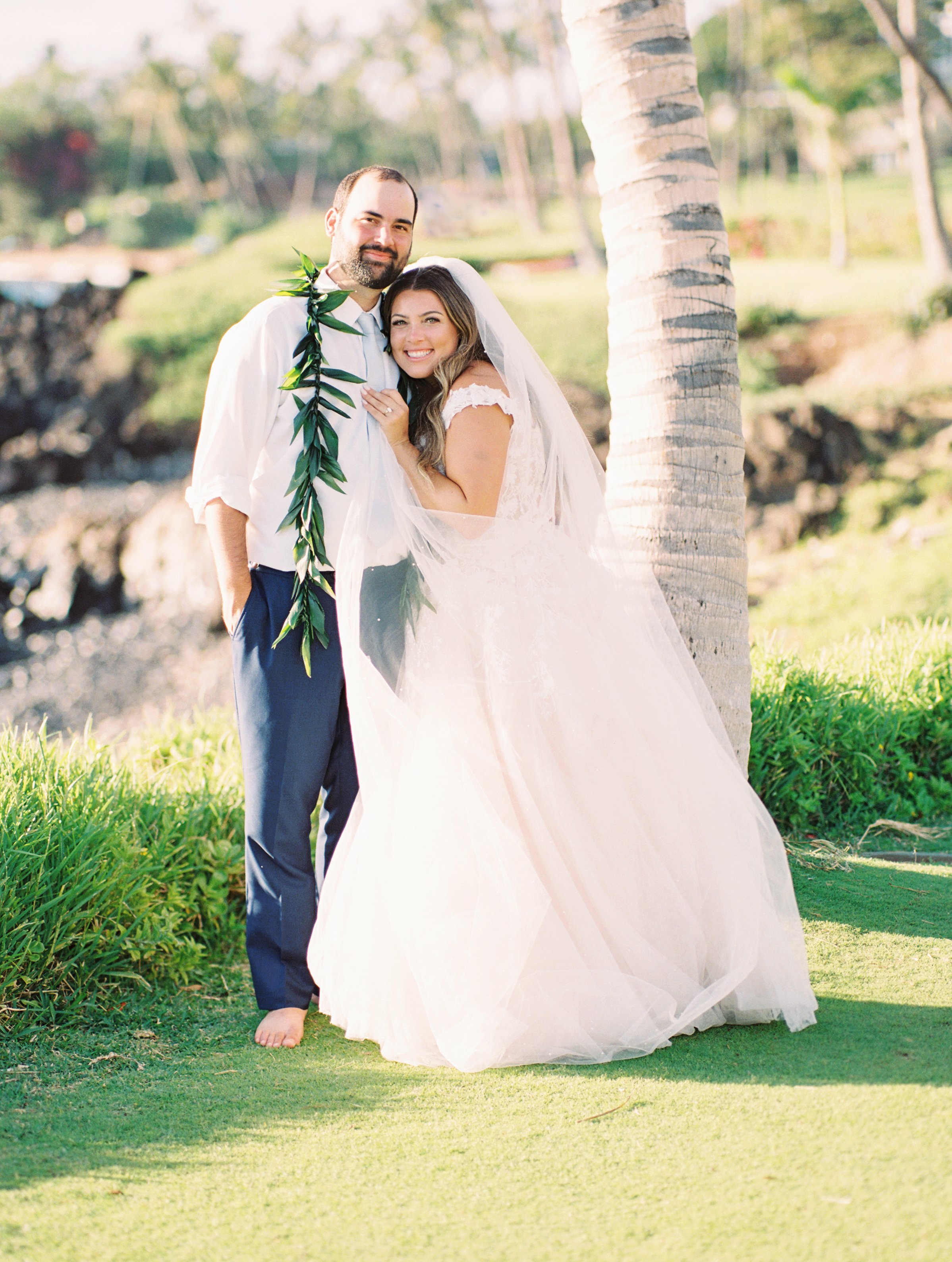A couple embracing with the Maui coastline in the background after their wedding at the Wailea Beach Resort.