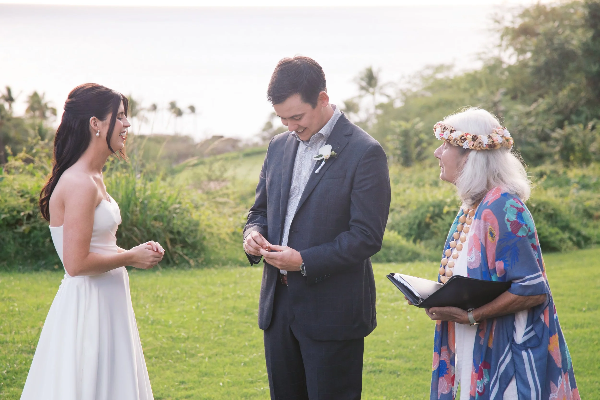 A bride and groom exchange rings during a golden hour wedding ceremony at Gather on Wailea