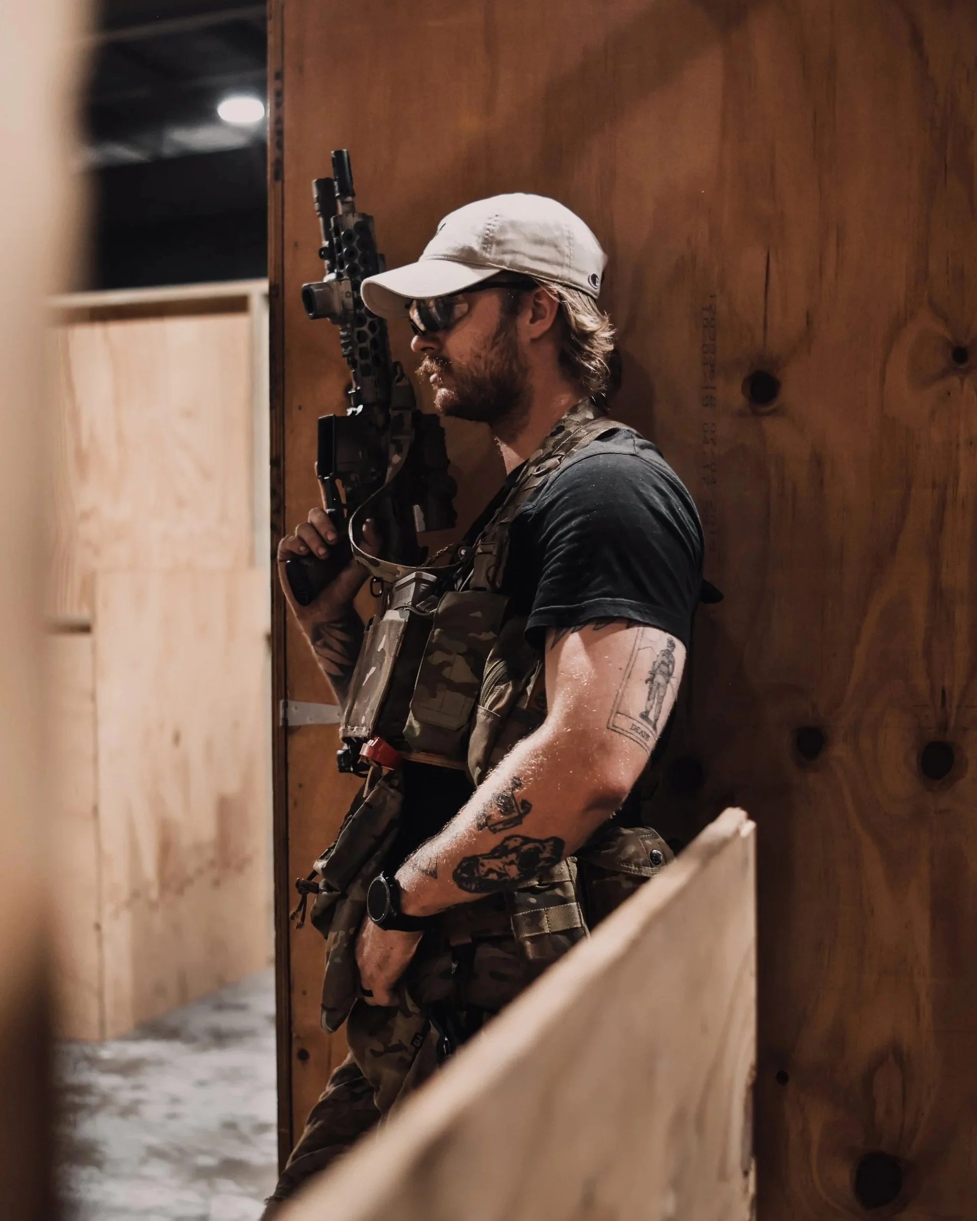 Group of individuals wearing tactical gear, holding guns, and standing on an outdoor staircase under a shelter with a green roof.