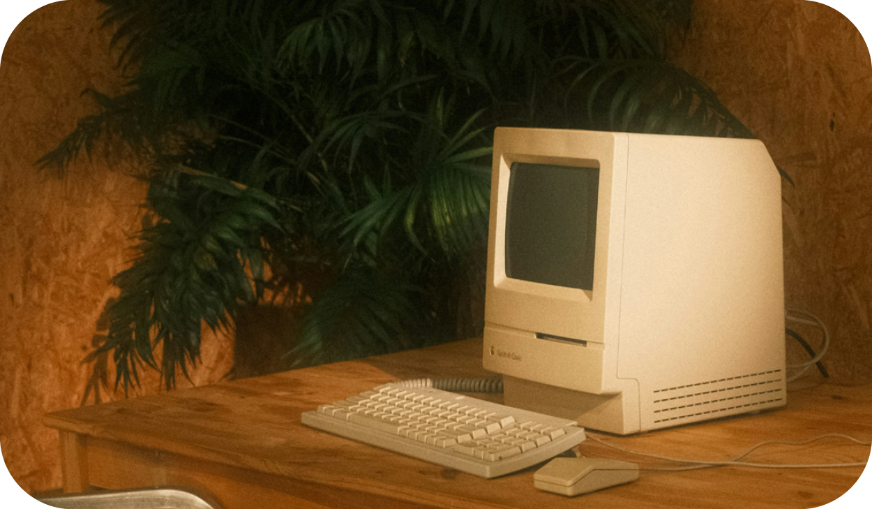 Retro looking computer and keyboard on a pine wood desk.