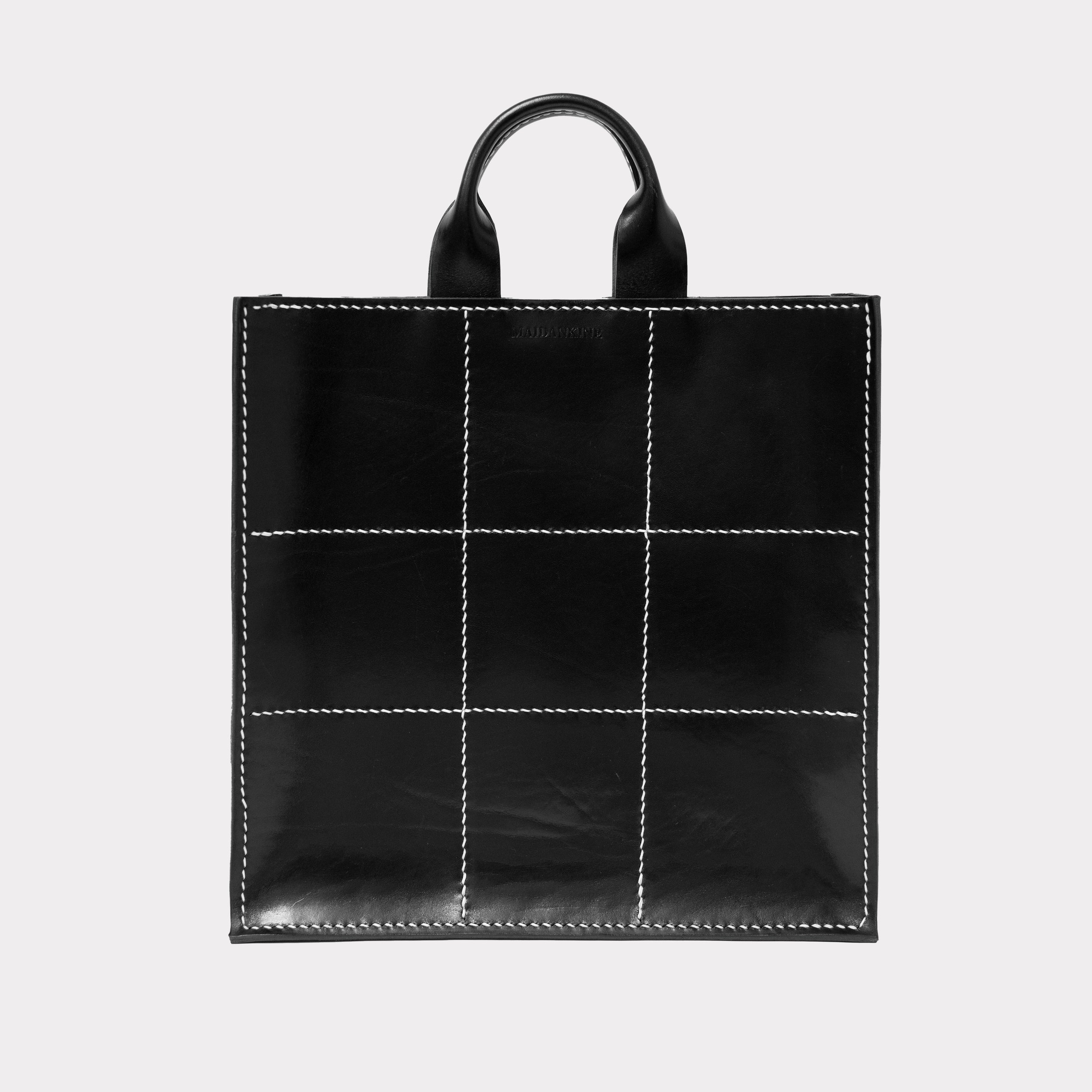 Black handbag with white grid stitching and two black handles