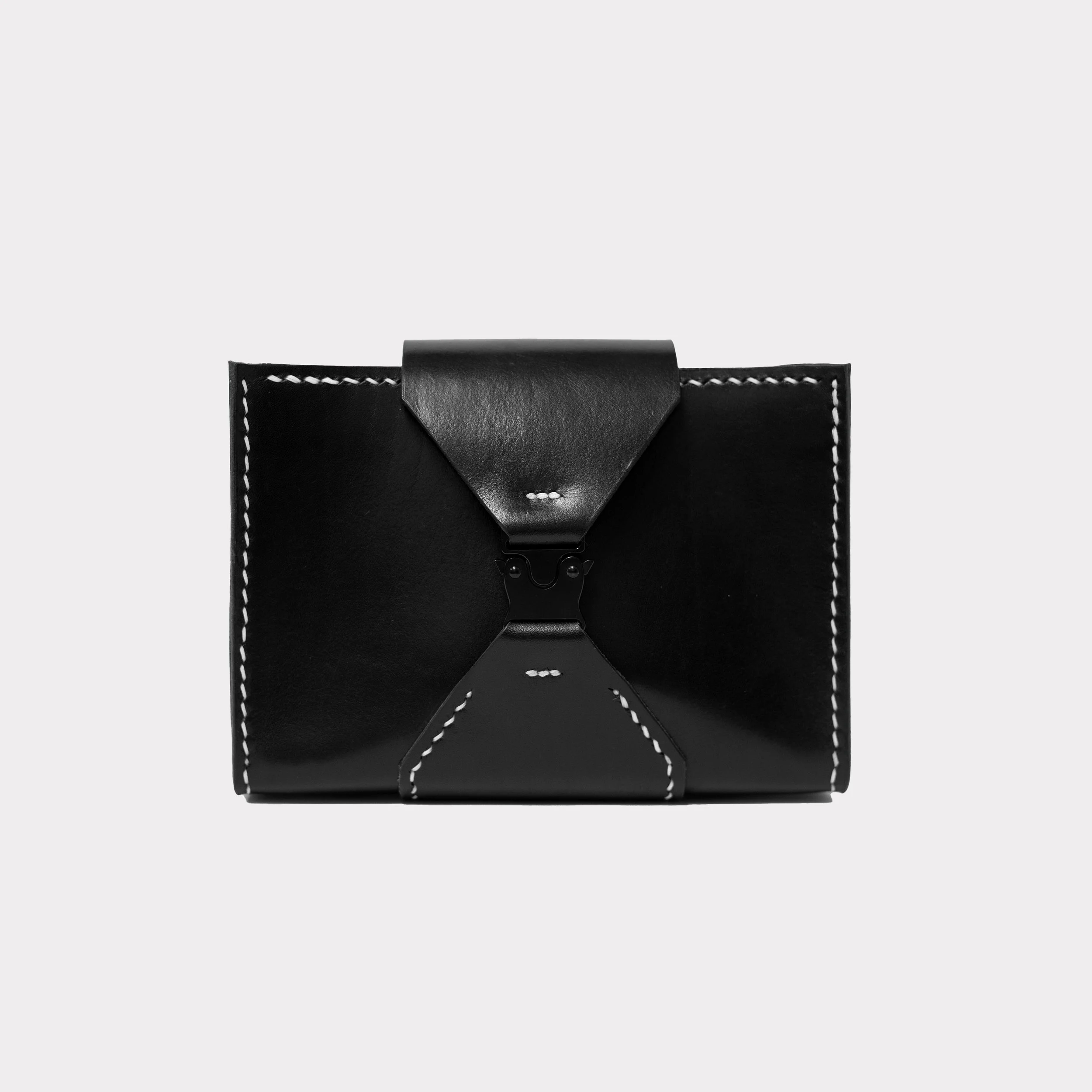 Small black bag with white stitching and a central clasp on a plain light gray background.