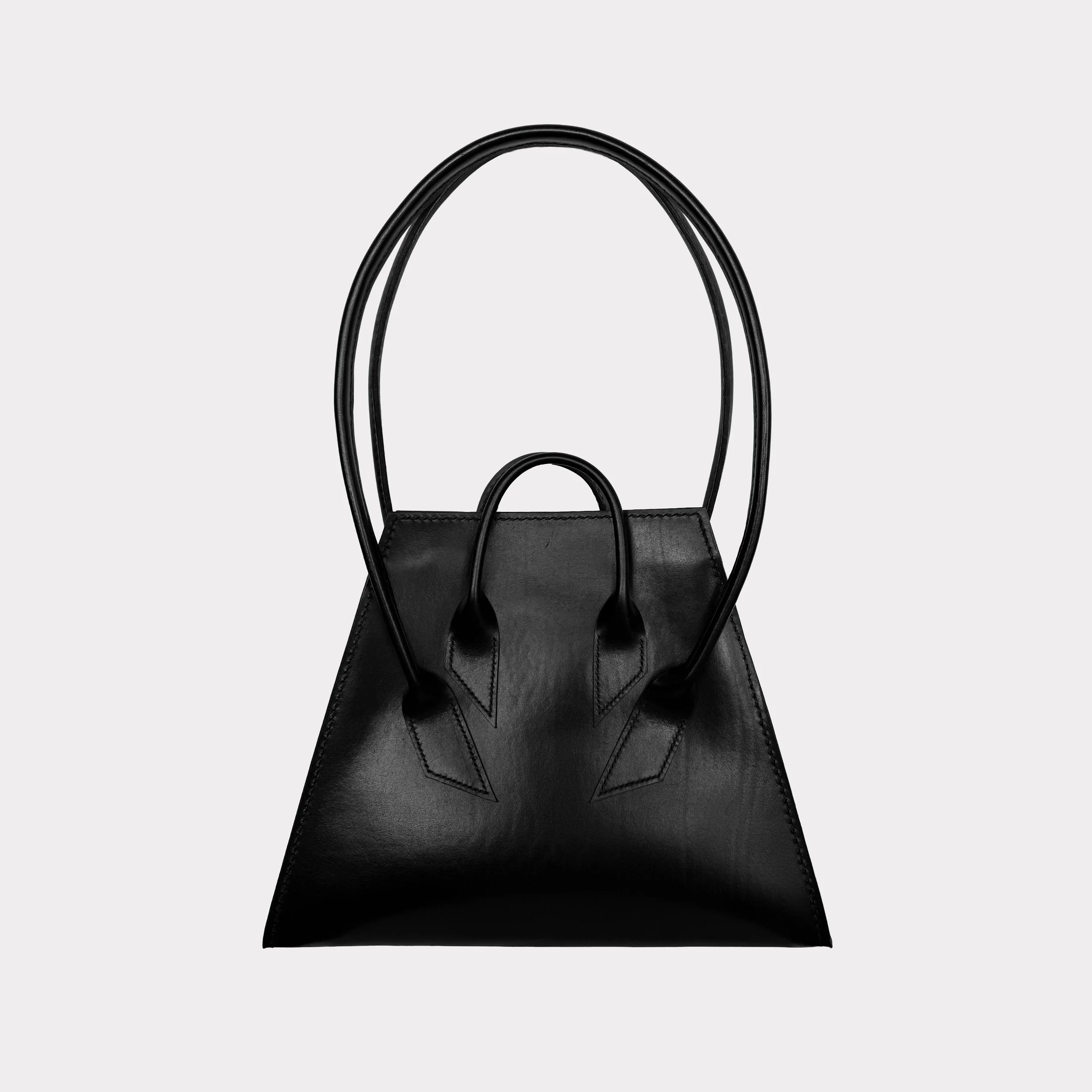 Black leather handbag with structured design and two top handles against a light gray background.