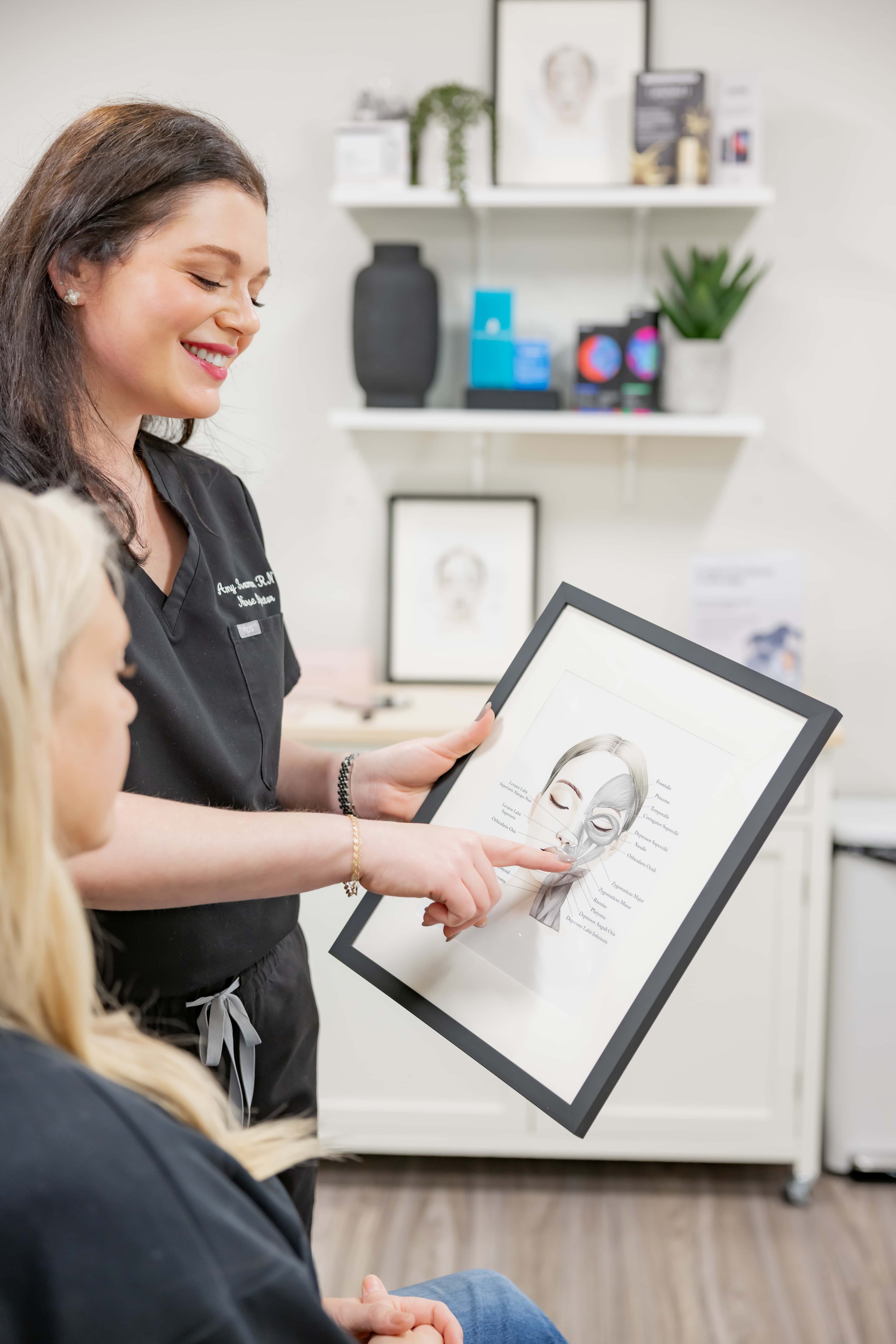 Amy Foxman, RN and Medical Aesthetic Provider at Morph Med Spa, reviewing a facial muscle diagram during a Botox consultation in Ridgefield, CT