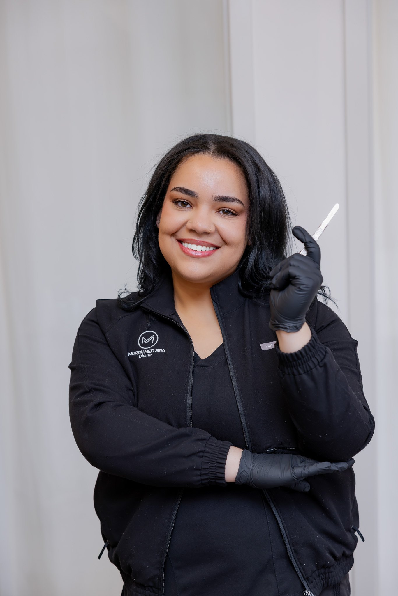 Divine Thomas, licensed esthetician at Morph Med Spa, holding a dermaplaning blade at the Ridgefield, CT location