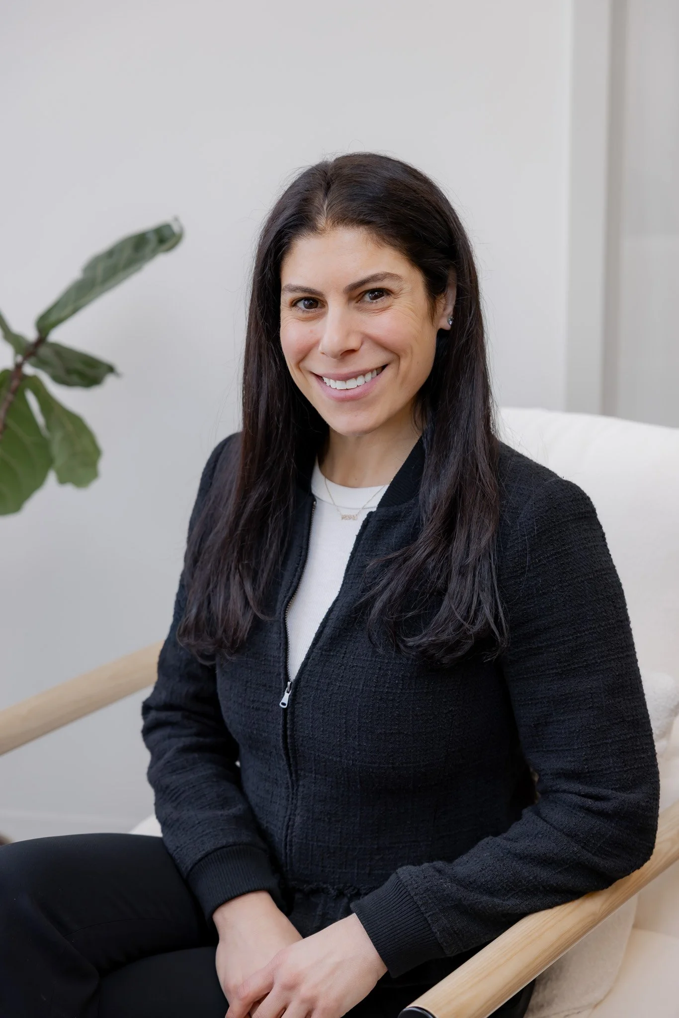 Melissa Rifkin, Registered Dietitian at Morph Med Spa, seated in a modern chair wearing a black zip jacket, smiling warmly in a bright office setting in Ridgefield, CT.