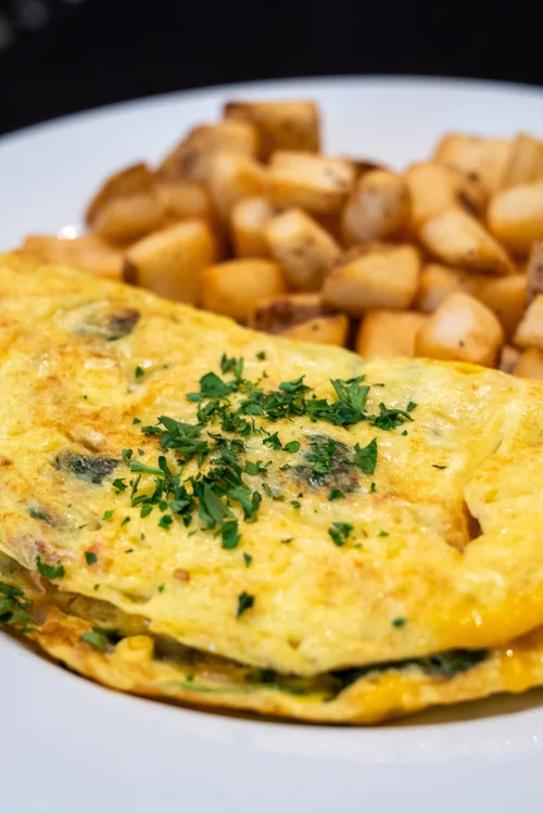 Omelette garnished with herbs and served with diced potatoes