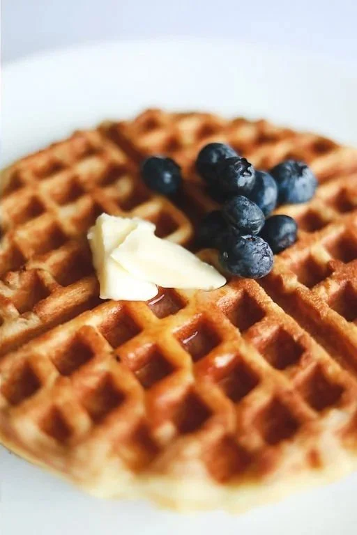 Waffle with Powdered Sugar and Blueberries and maple syrup. 