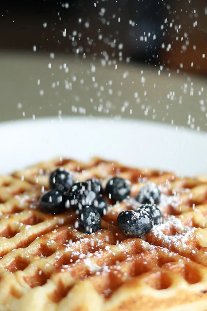 Waffle with Powdered Sugar and Blueberries and maple syrup. 