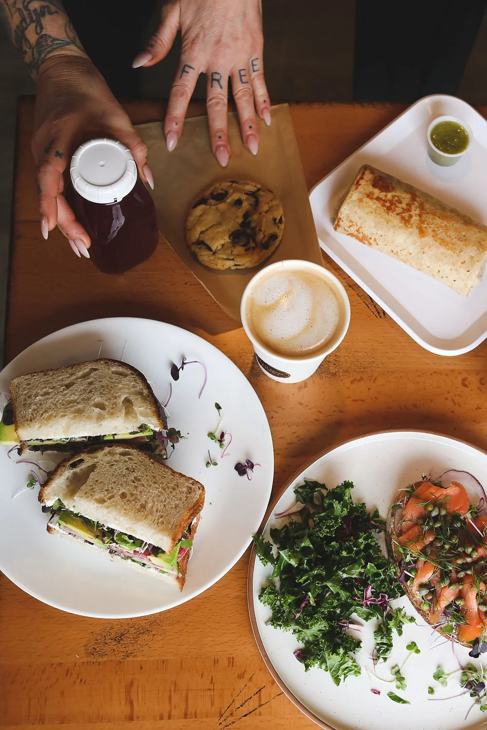 Midland Sandwich, Breakfast Burrito and smoked salmon on toast with capers, along with a latte, fresh juice and chocolate chip cookie. 