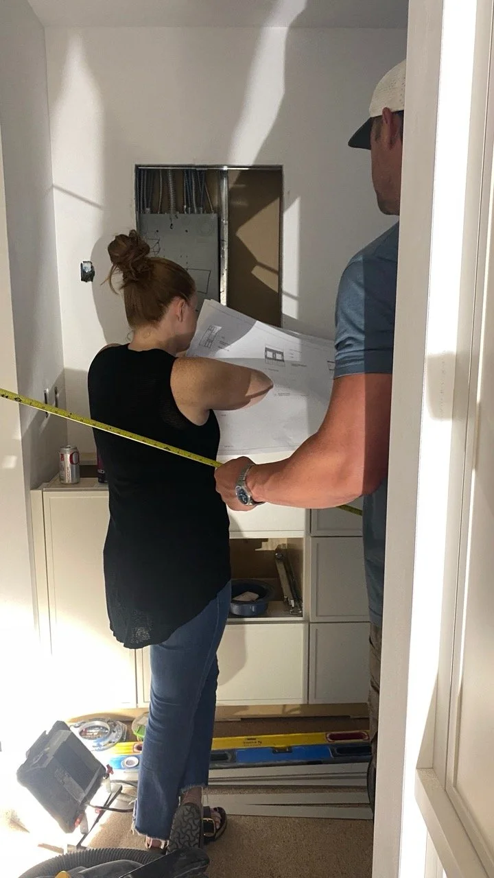 Flemming Interiors reviewing architectural drawings and taking on-site measurements during a Cherry Creek condo renovation to confirm custom cabinetry and interior architecture details.