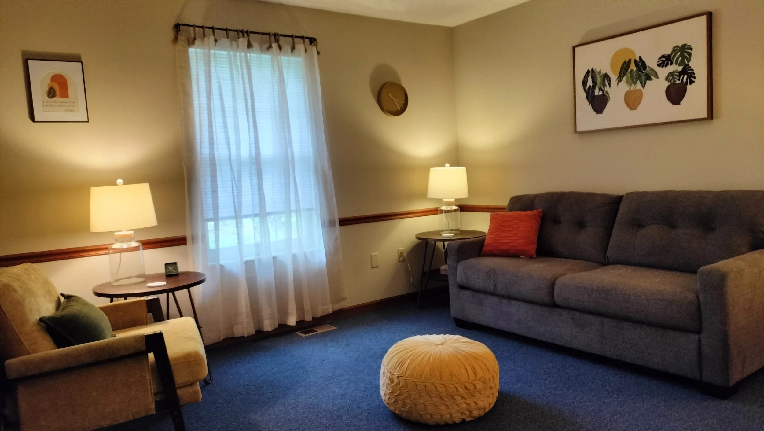 Therapist's office with chair, couch, 2 side tables with lamps, a window and an ottoman