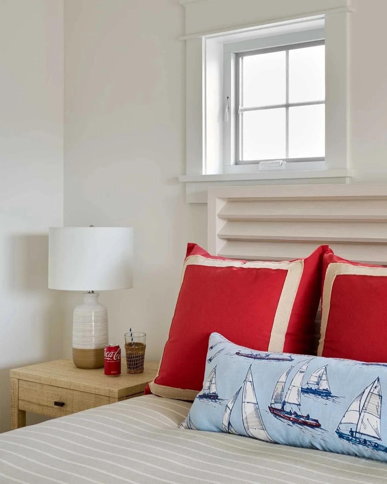 Bedroom with red square pillow and nautical decor.