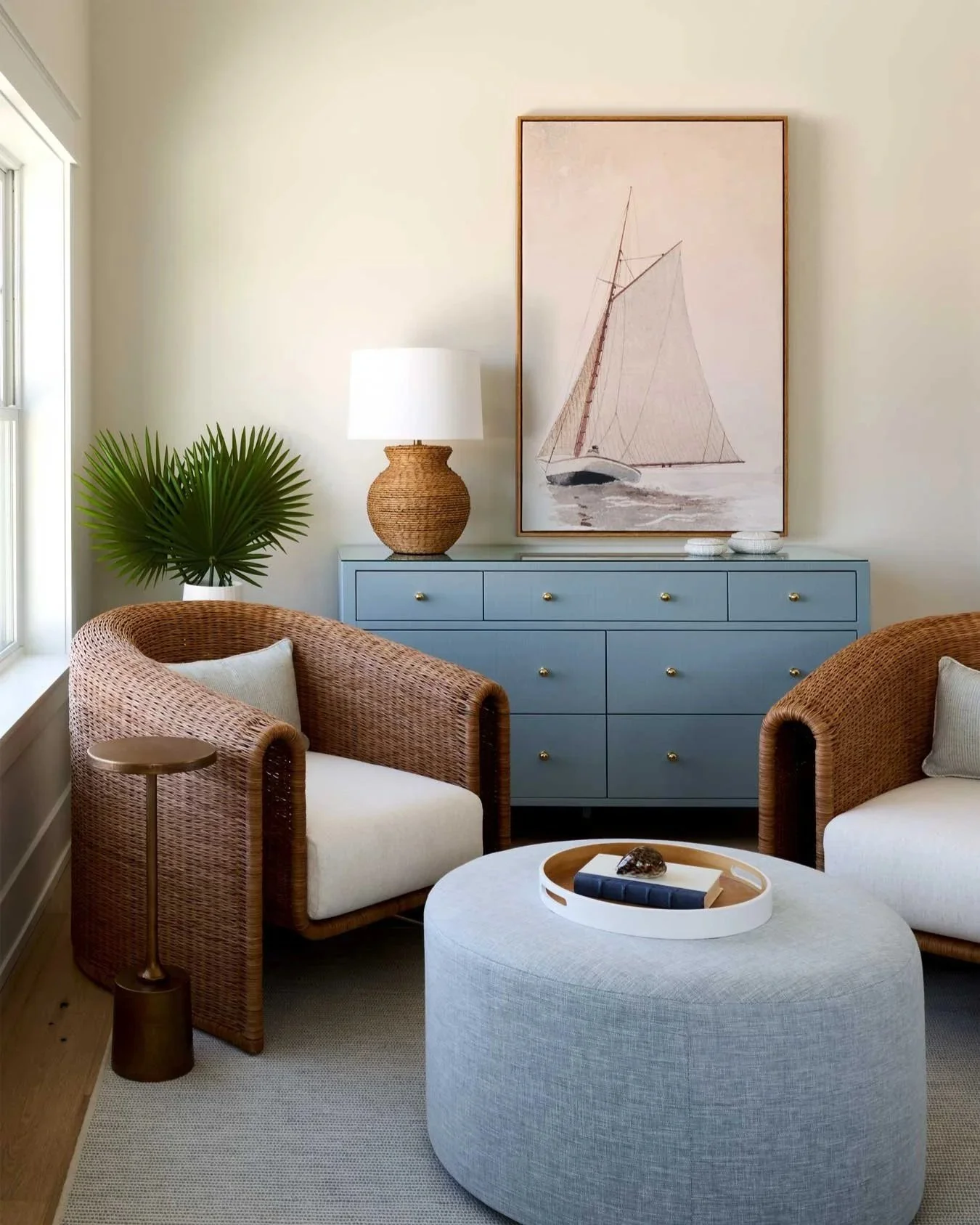 Cozy seating area with sailboat print on a blue dresser.