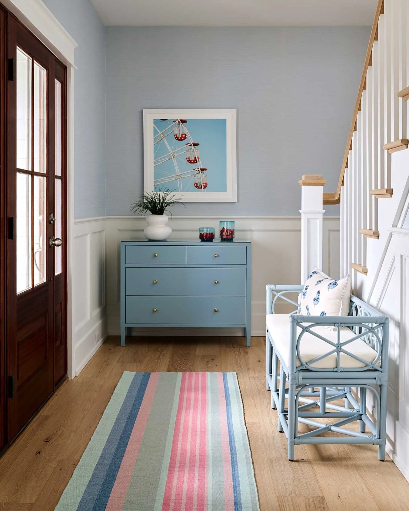 Entry way with striped rug and blue bench.