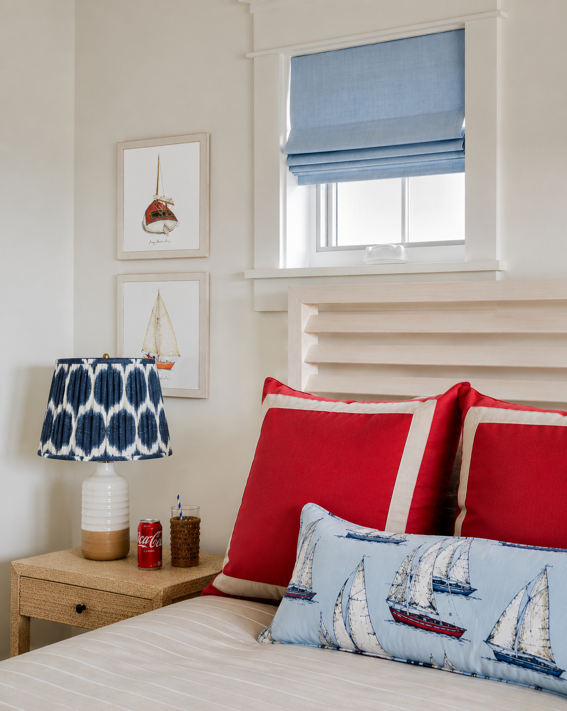 Red, white, and blue bedroom with red square pillow and nautical decor.