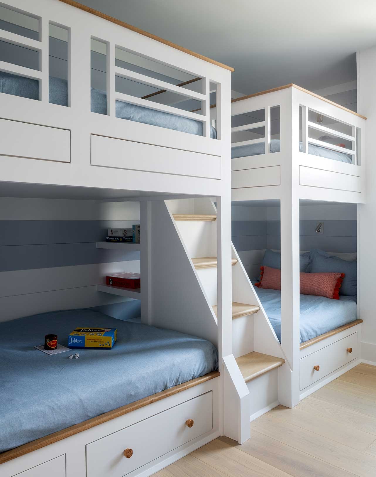 Bunk beds with white frames, blue bedding, and wooden trim in a child's room.