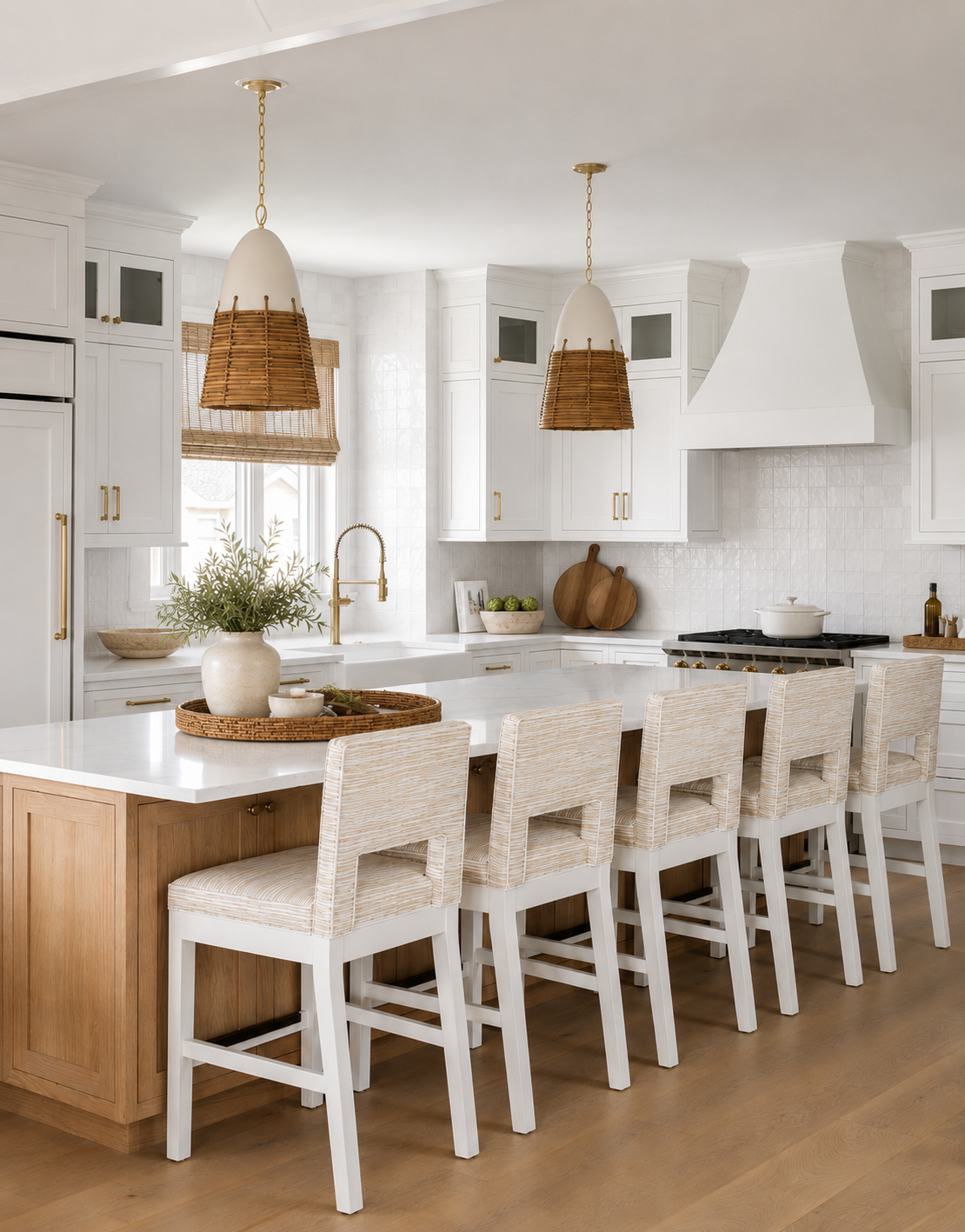 Modern white kitchen with island and seven bar stools, pendant lights, and cabinetry.