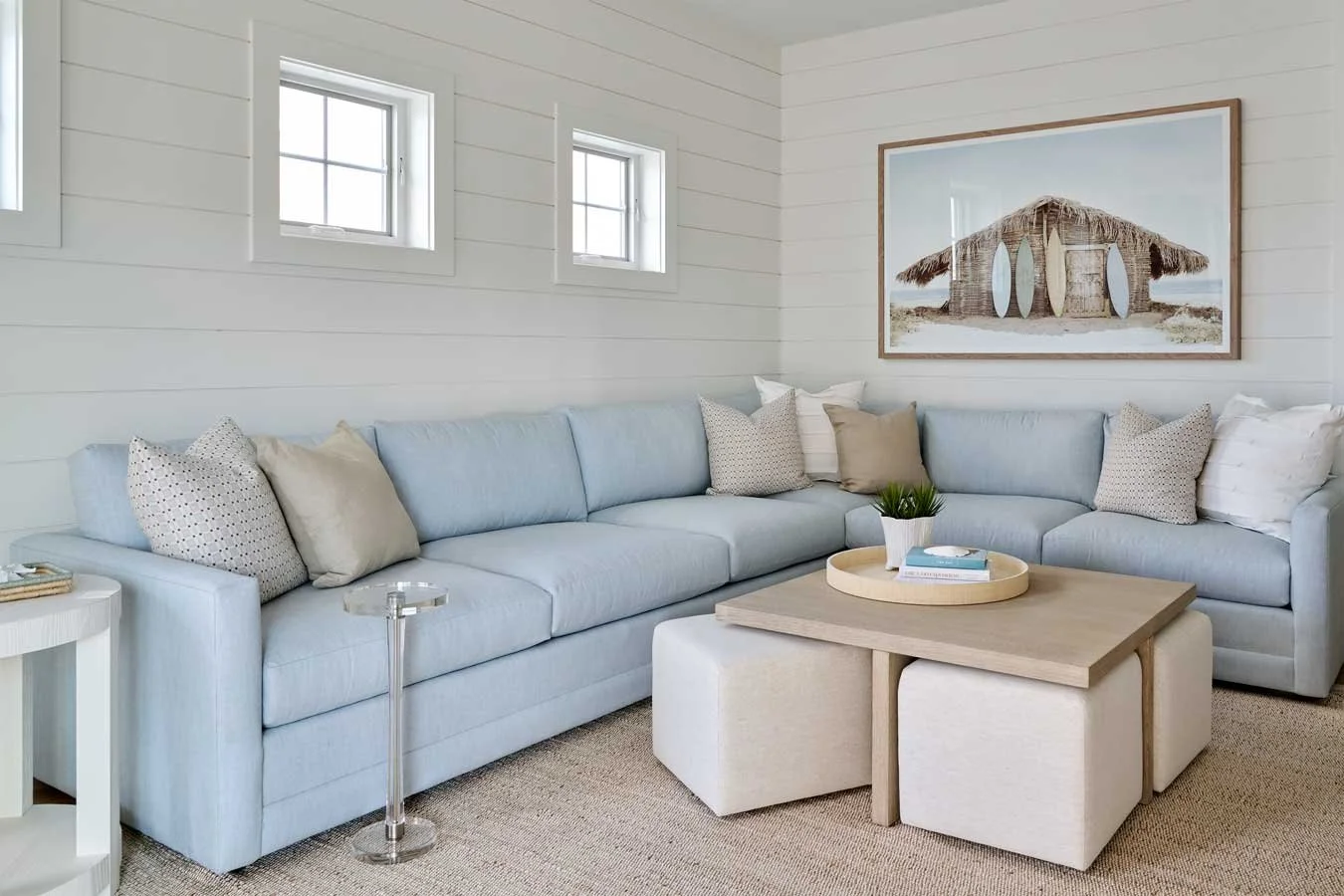 Family room with large blue sofa and coffee table with four stools underneath.