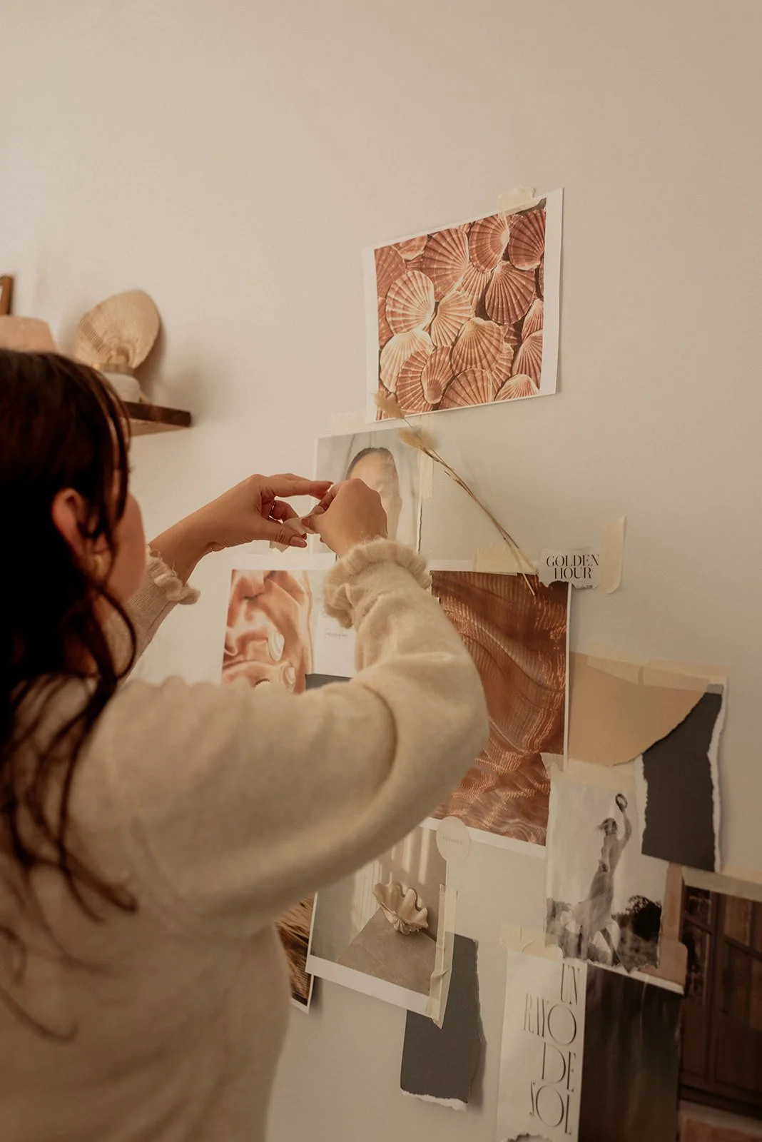 Woman-attaching-pictures-to-a-wall-moodboard