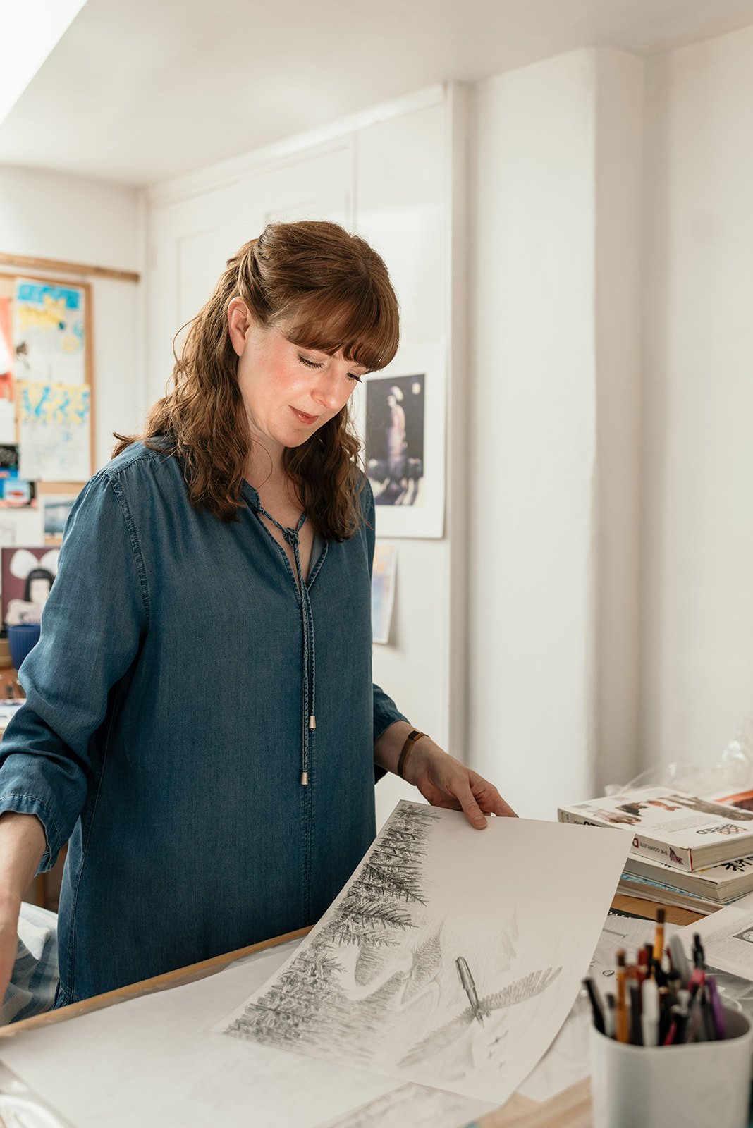 A female artist looking at her work in her studio.