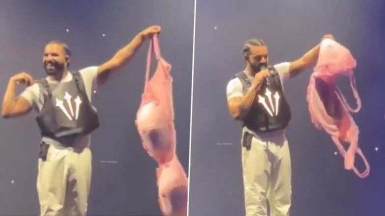 Performer on stage holding a large pink bra.