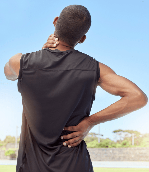 Back view of a man in athletic wear touching his neck and lower back outdoors.