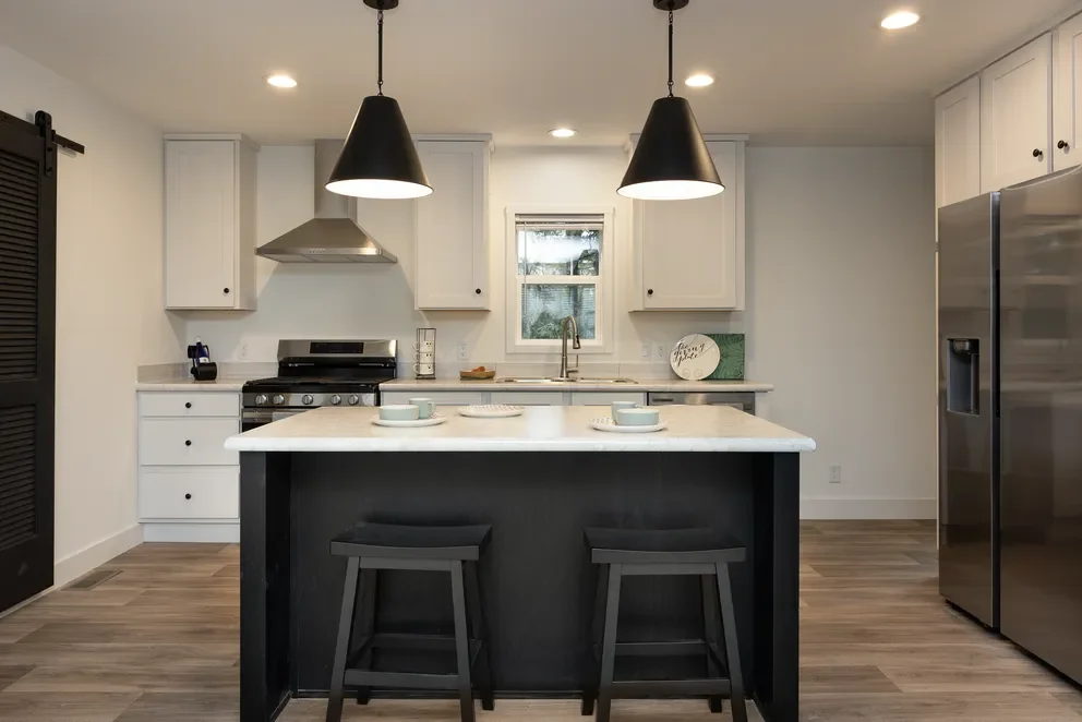 photo of kitchen with white island and white cabinets in the hey jude manufactured home 