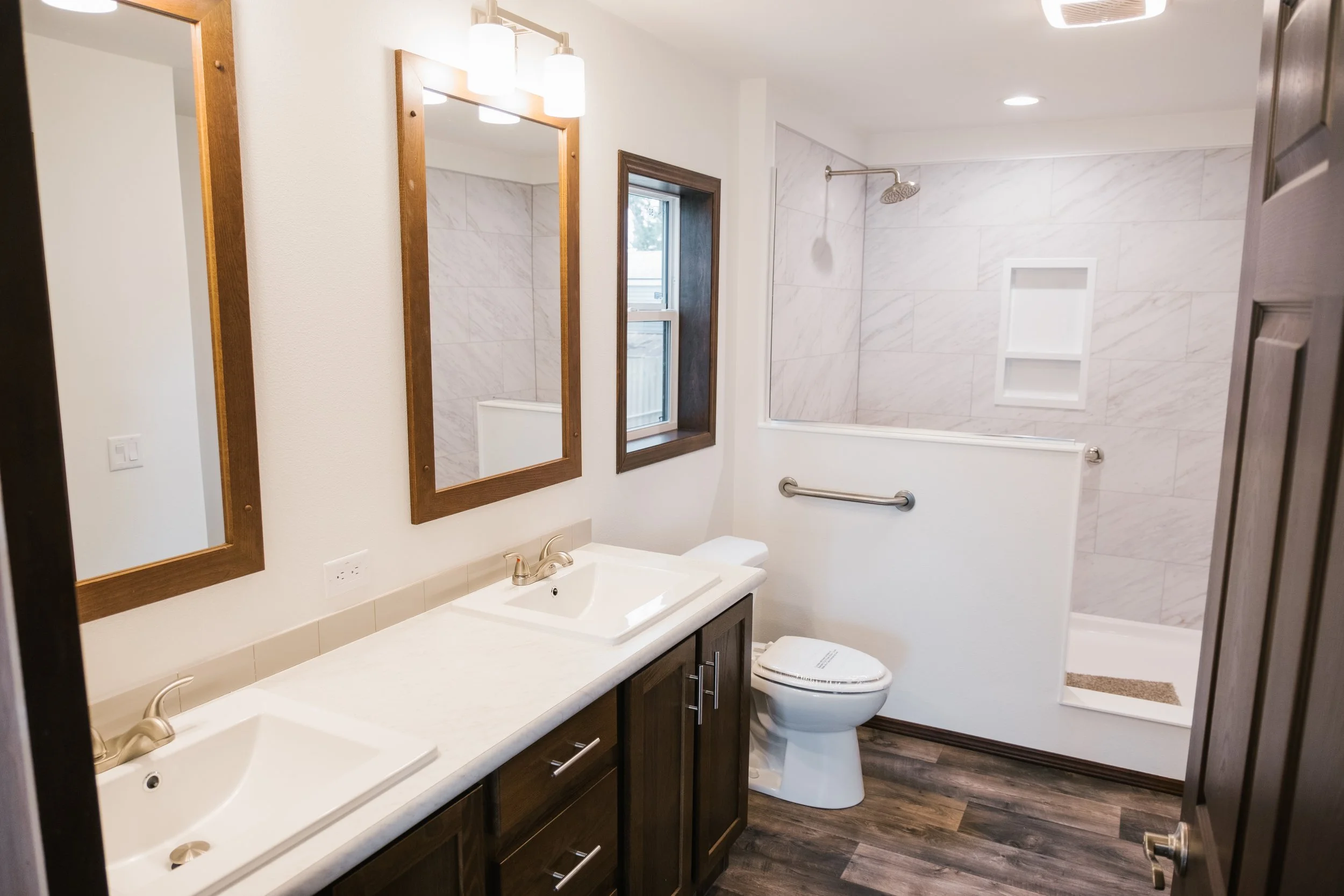 master bathroom photo with duel vanity and large walk in tiled shower with a half wall