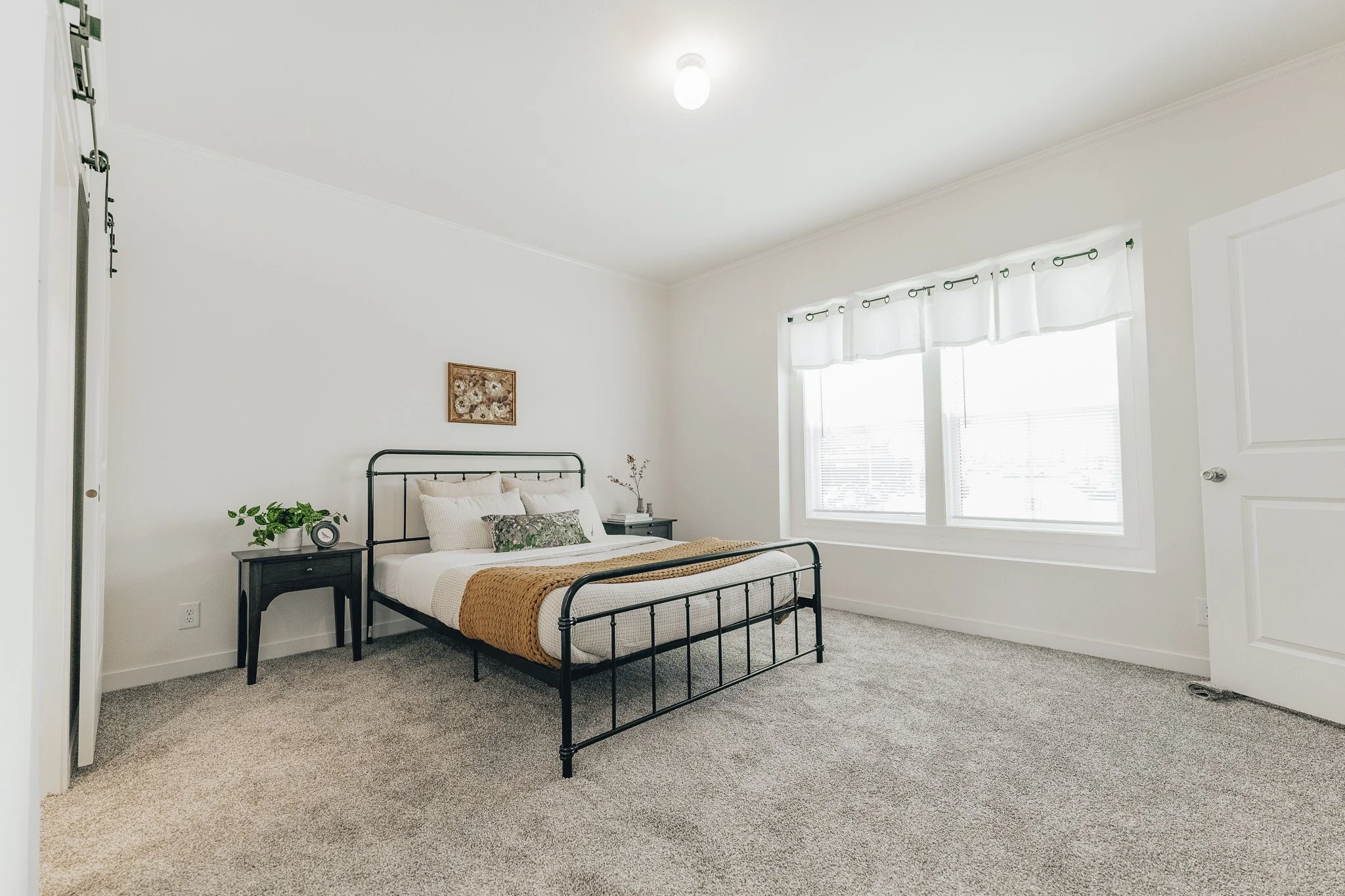 master bedroom photo with bed and barndoor inside the cavco farmhouse manufactured home