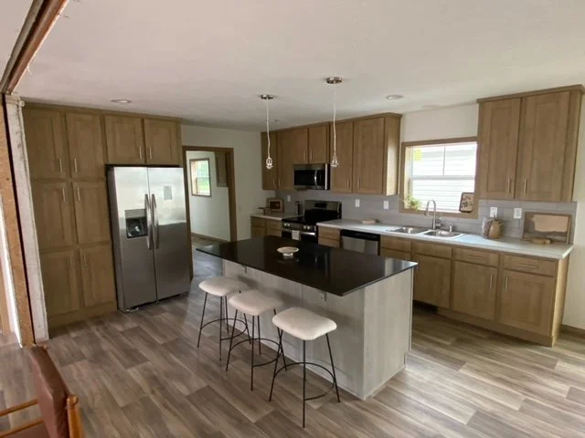kitchen photo with light brown cabinet with gray island with black granit countertop 