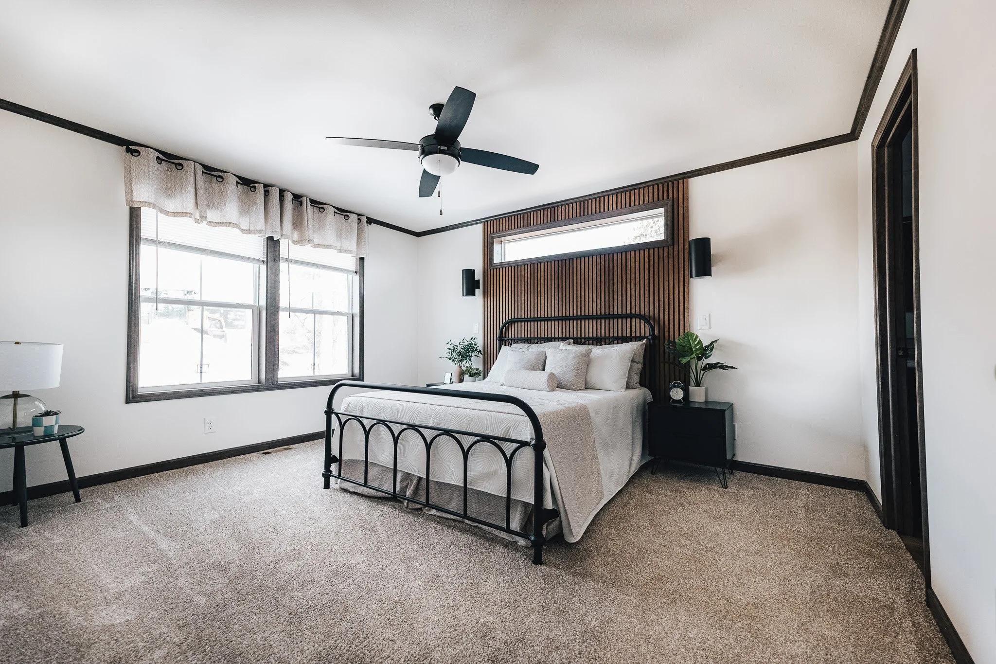 Master Bedroom photo with queen sized bed and vertical wood wall with transom window over the bed in the Cavco Westlake Retreat 
