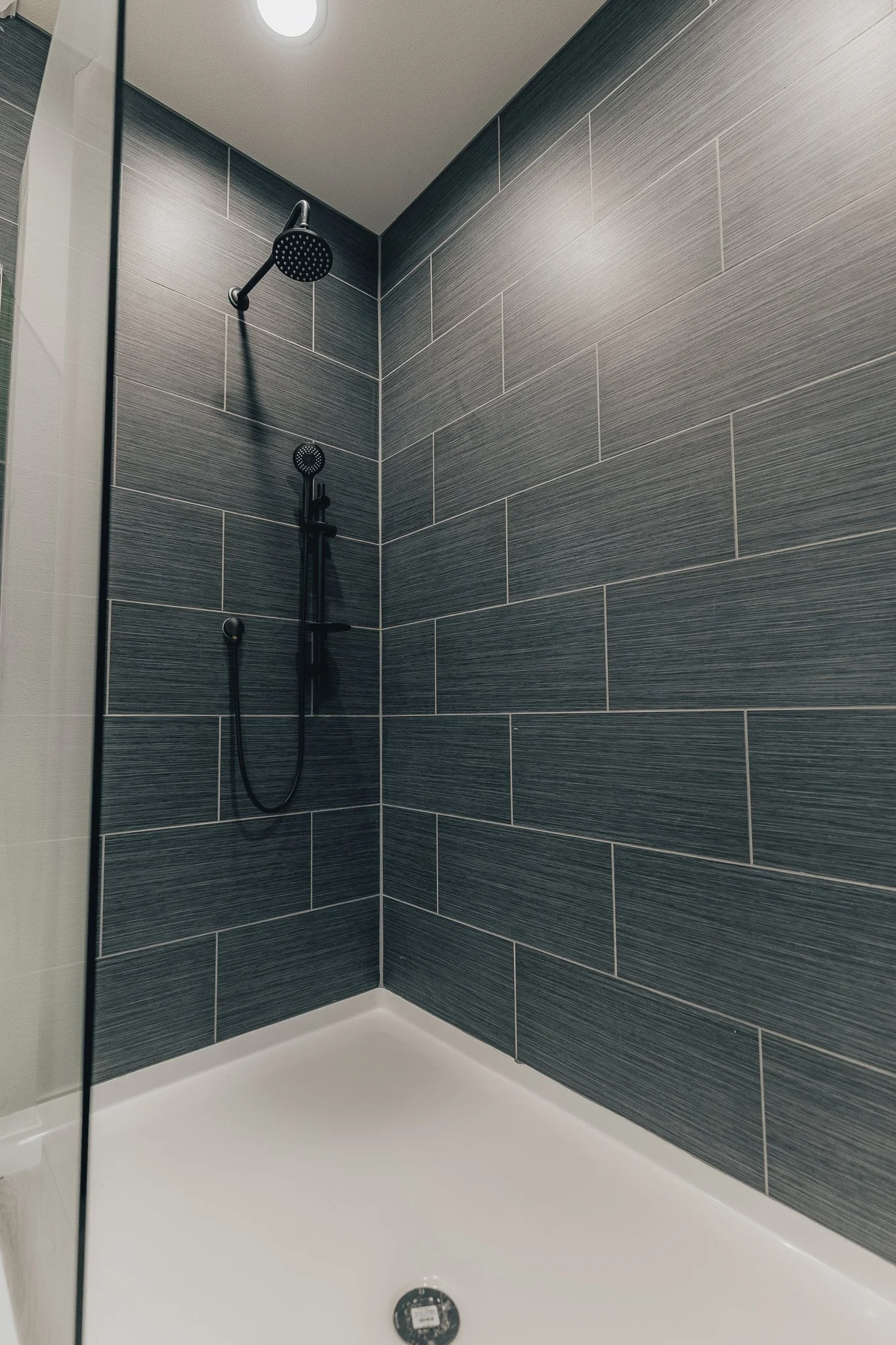 black tiled shower with glass half wall