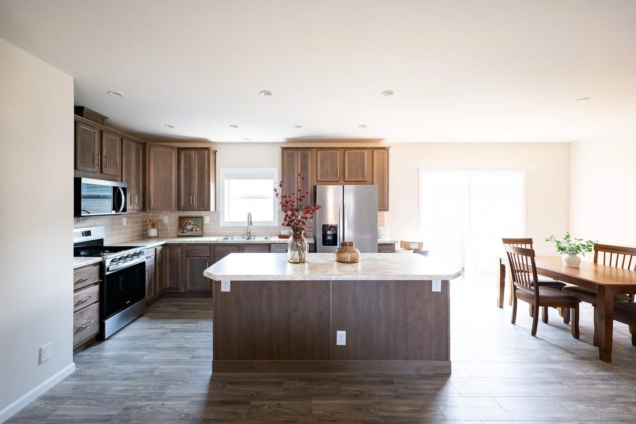 kitchen photo with brown cabinets and a large island with a dinning room in view inside the kitchen of the bonnavilla limited series 
