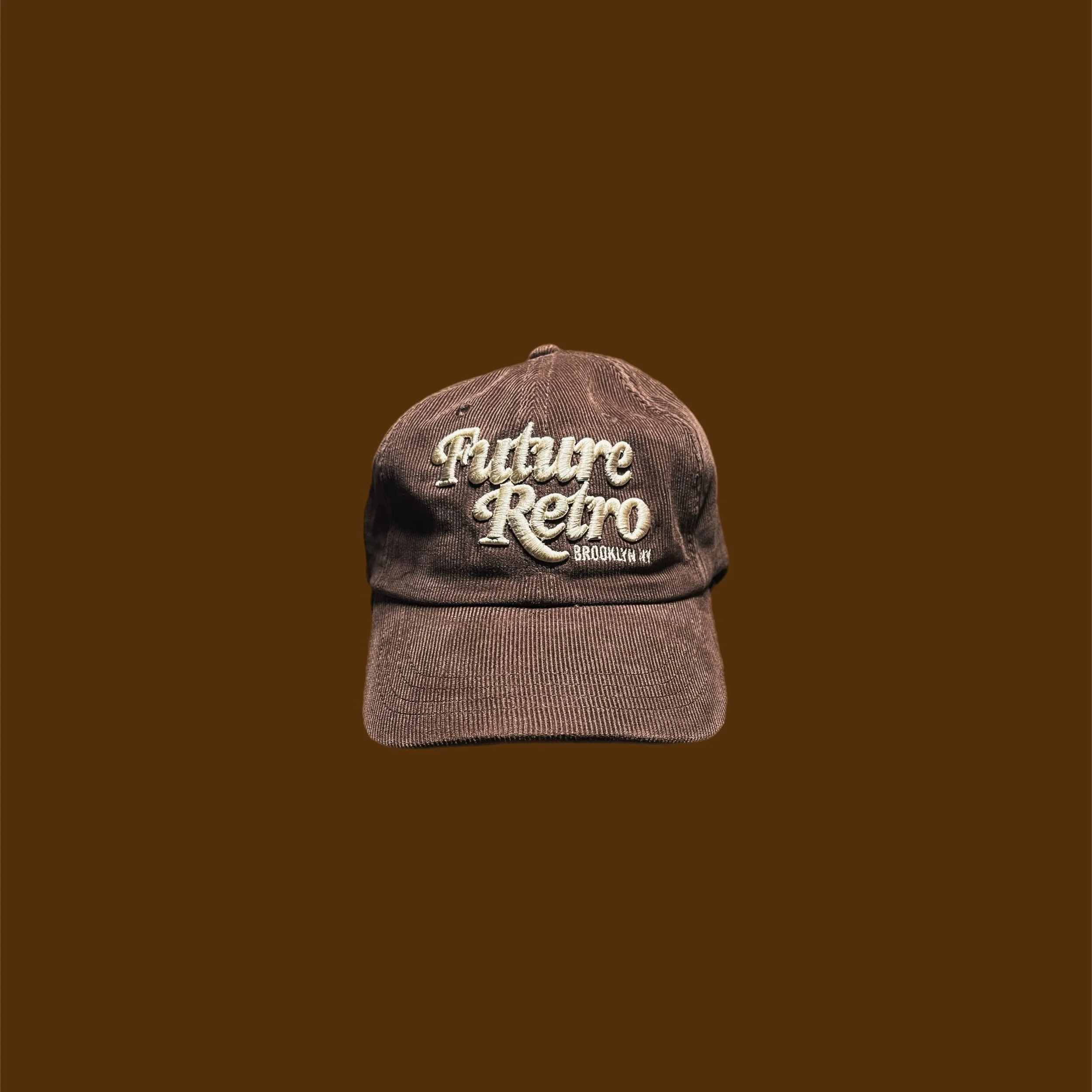Brown vintage-style baseball cap with embroidered text 'Future Retro Brooklyn NY' on the front, against a solid brown background.