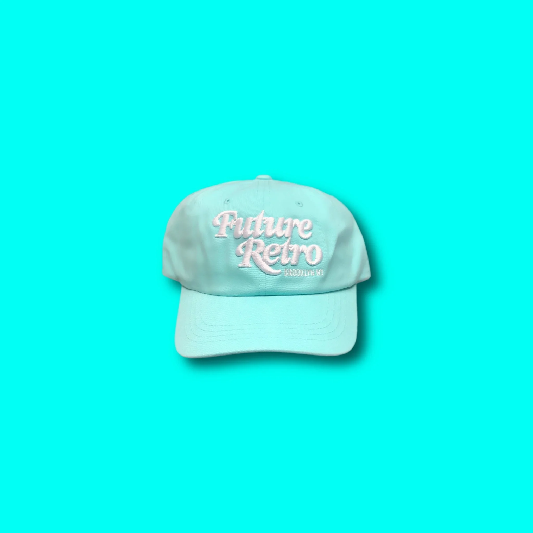 Light blue baseball cap with embroidered white text that reads 'Future Retro Brooklyn NY' on a bright cyan background.