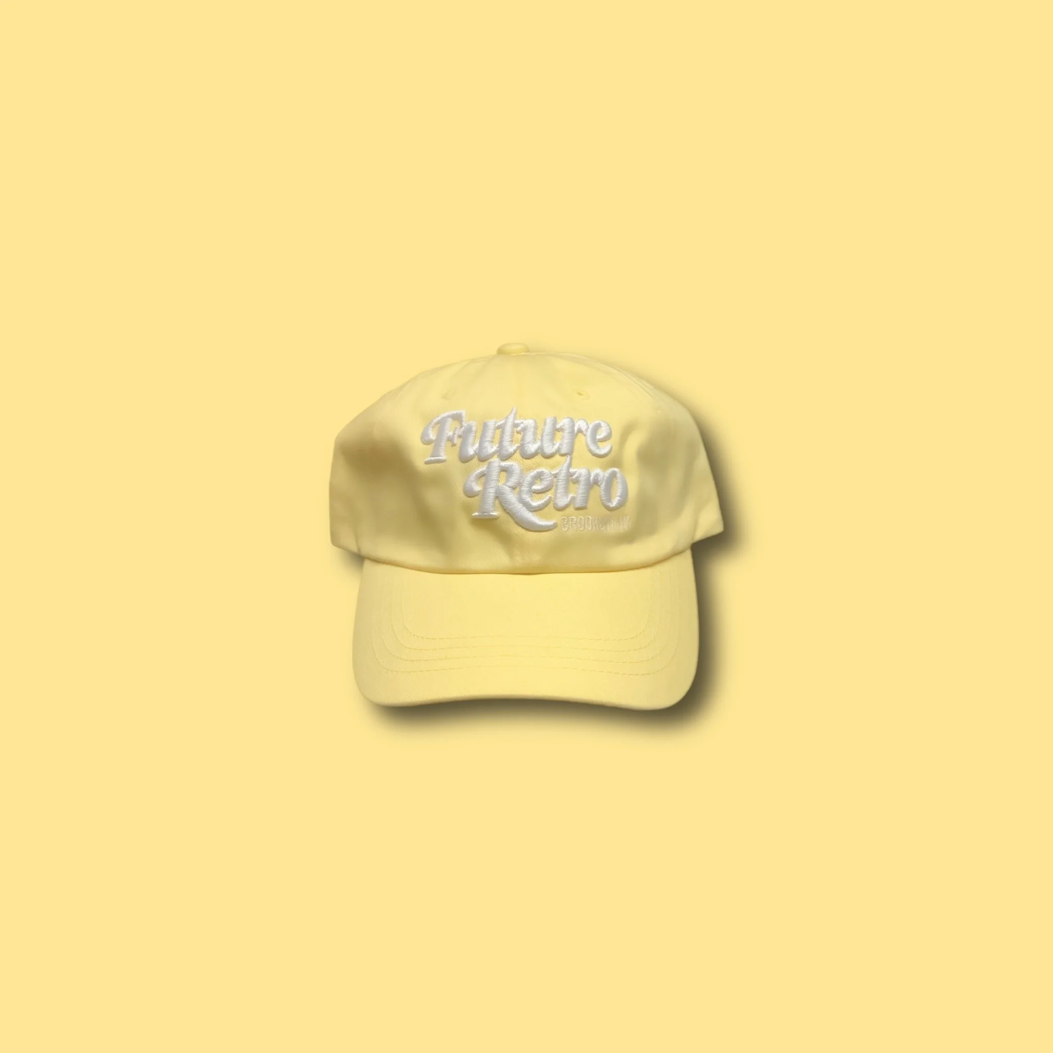 Yellow cap with embroidered text 'Future Retro' on the front against a matching yellow background.