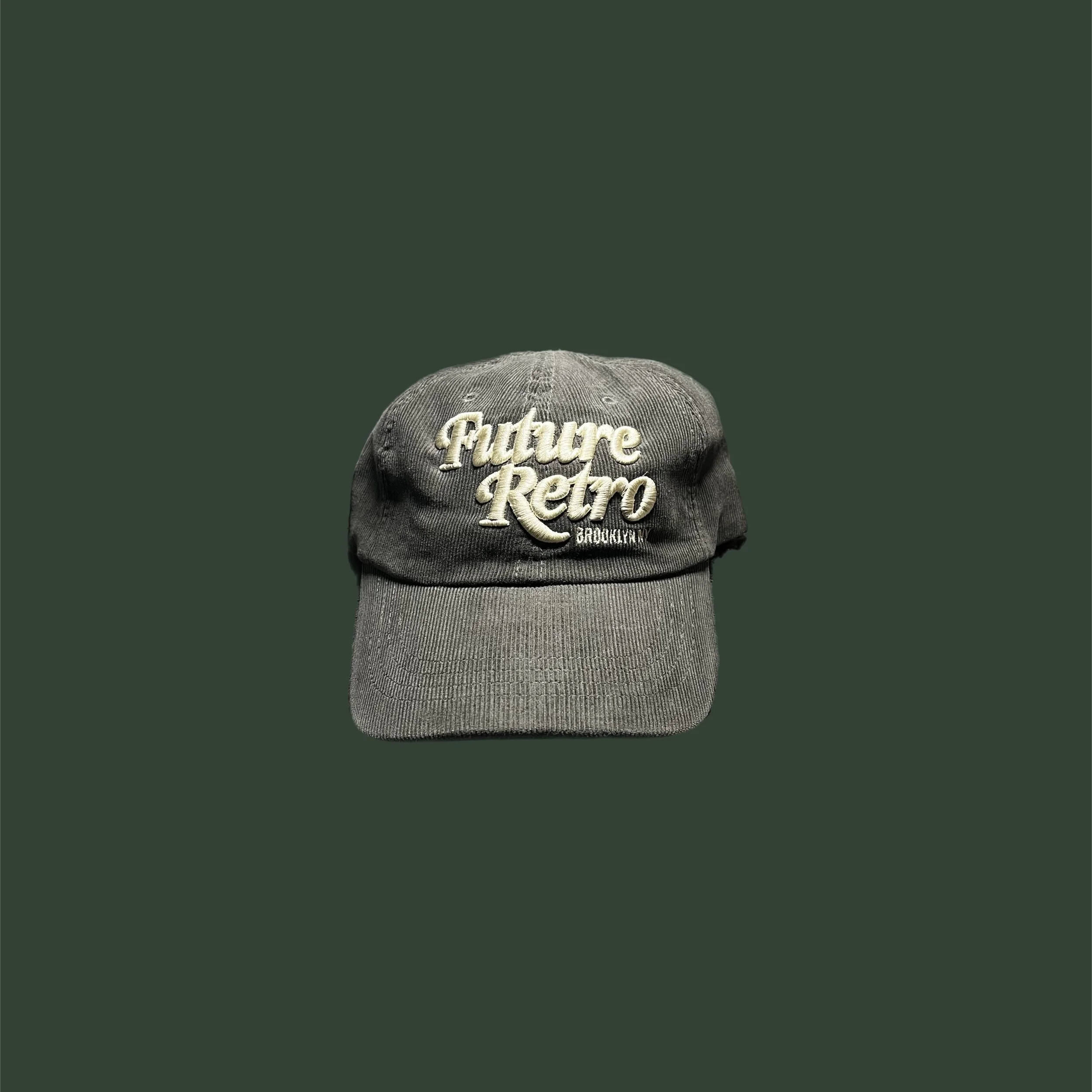 Gray baseball cap with embroidered text 'Future Retro Brooklyn' on the front, set against a dark green background.