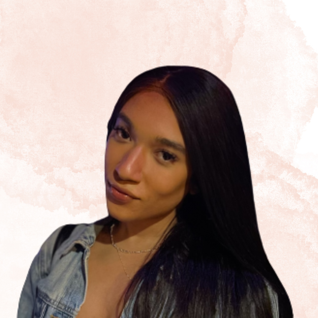 portrait of young woman with long straight black hair, wearing a denim jacket, looking at the camera against a light pink abstract background.