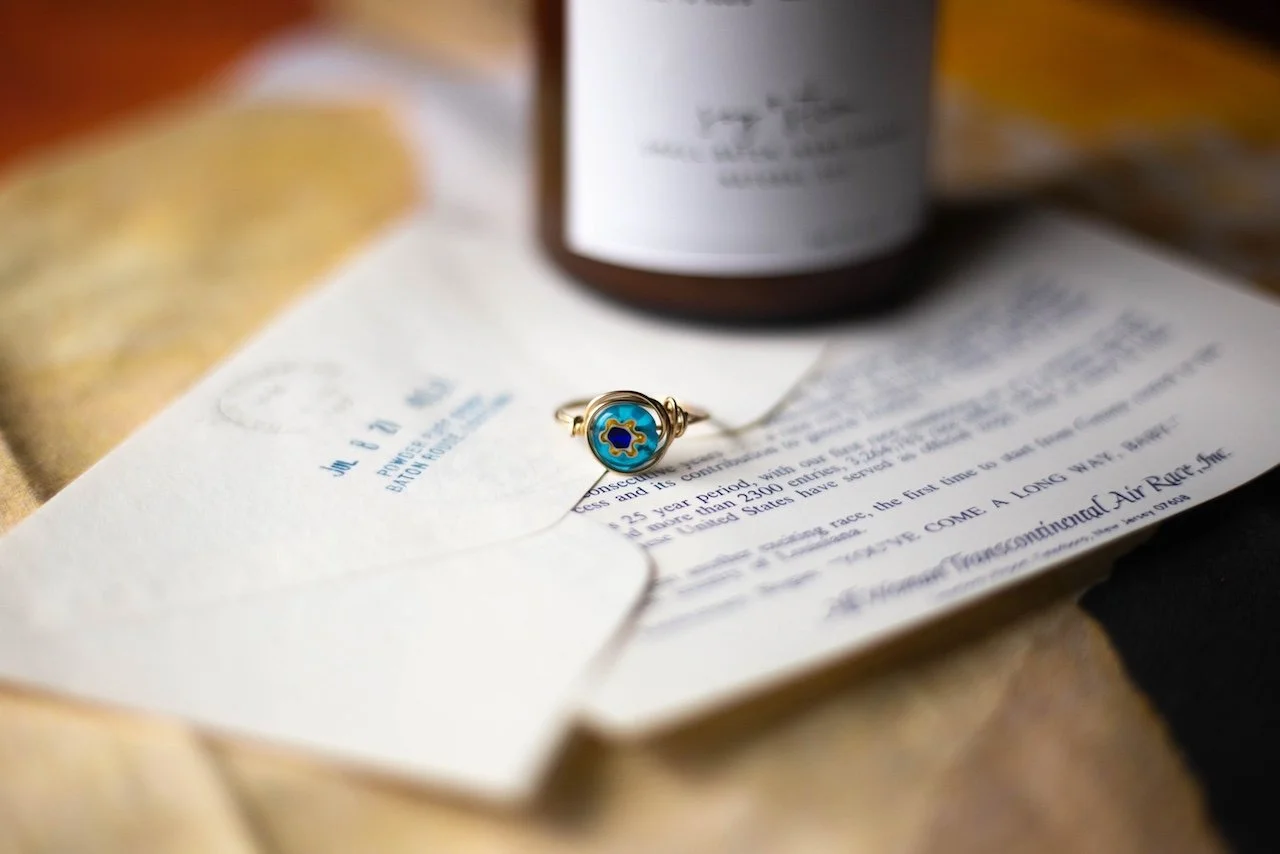 Decorative ring on vintage-style stationery with text and an envelope, background with bottle.