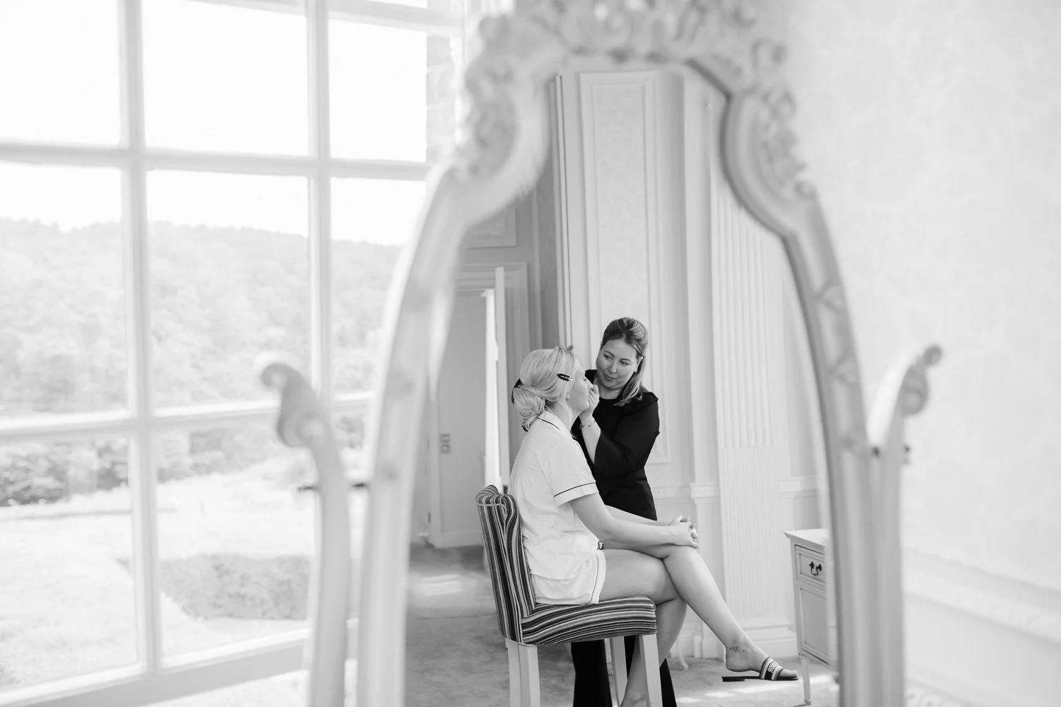 Black and white photo of bride having her makeup done at Hedsor House