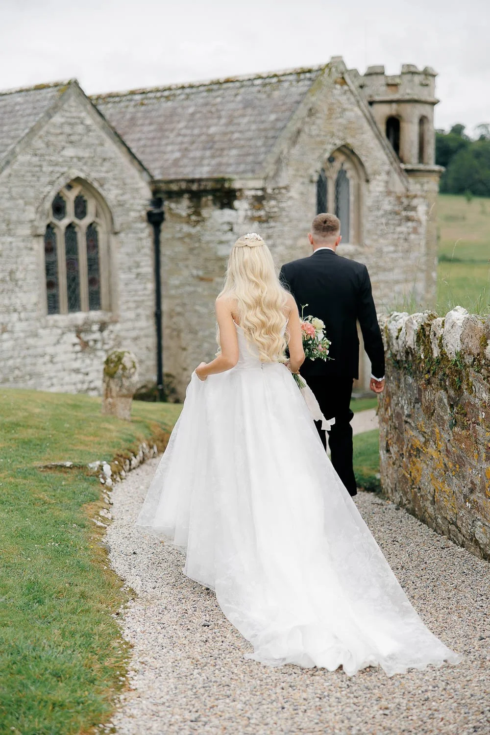 Bride and groom walking by the church at Boconnoc