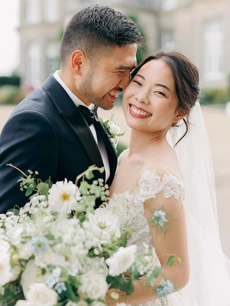 Fine Art Wedding Photography - close portrait of a Bride holding a white and green bouquet and a Groom in black tie on their wedding day