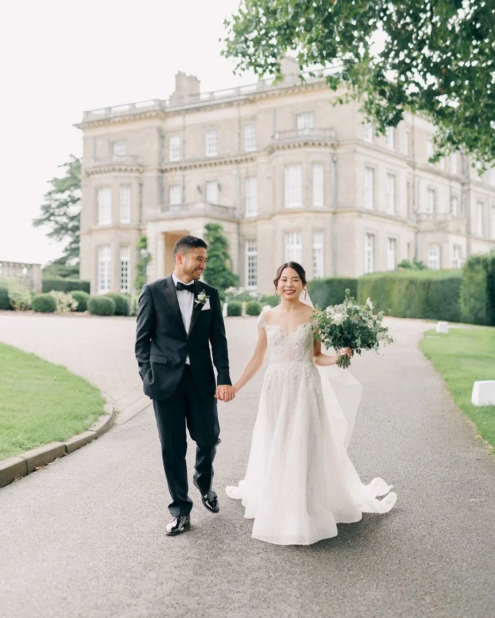 Fine Art Wedding Photography - Light and airy photo of a groom walking in front of a manor house in the UK