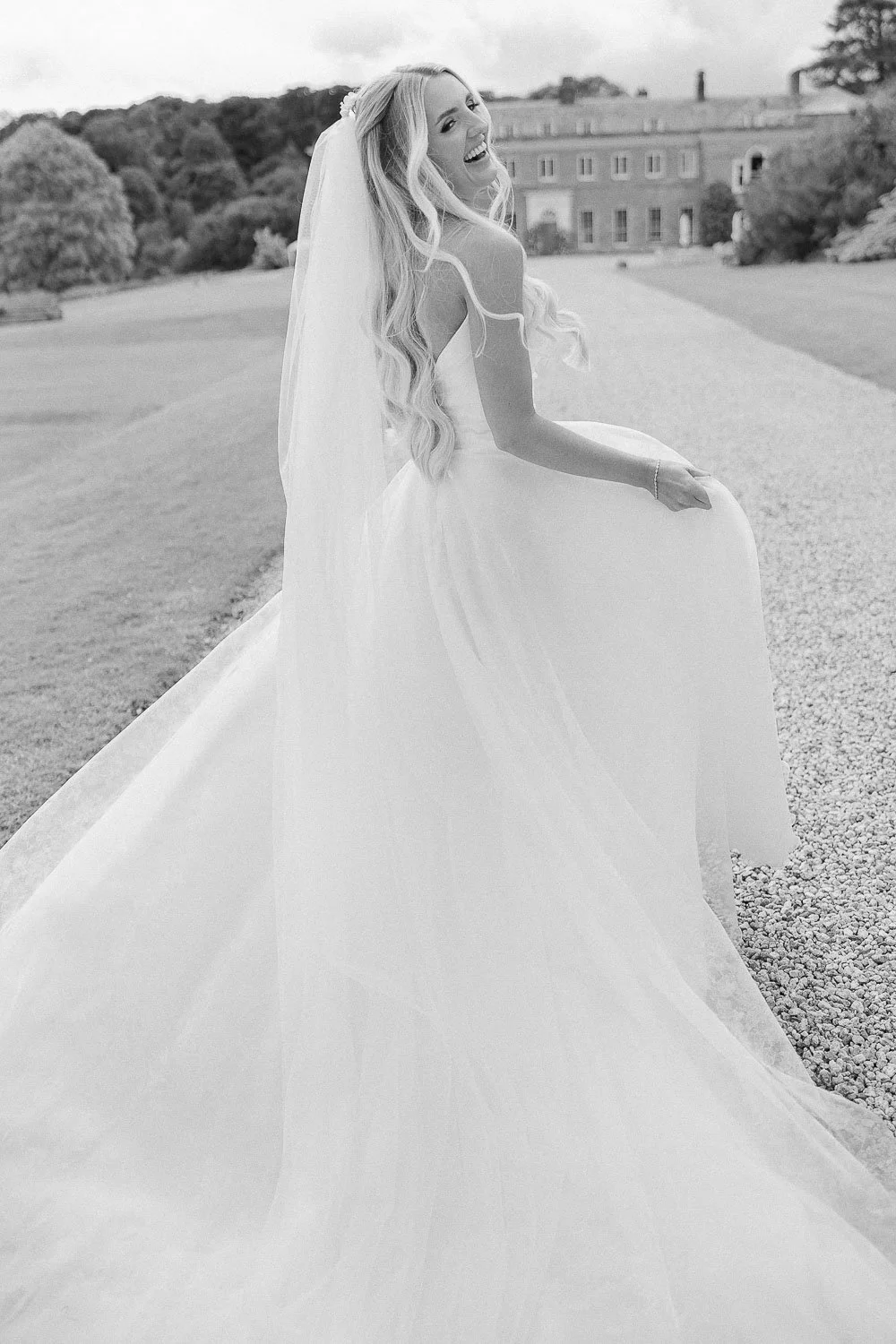 Bride running whilst holding her dress, in front of boconnoc estate