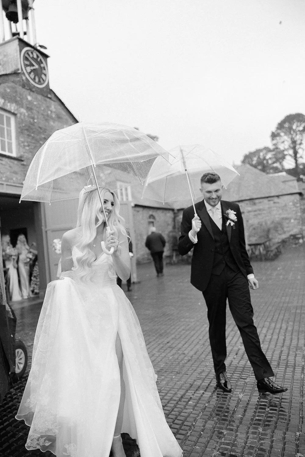 bride and groom with umbrellas smiling