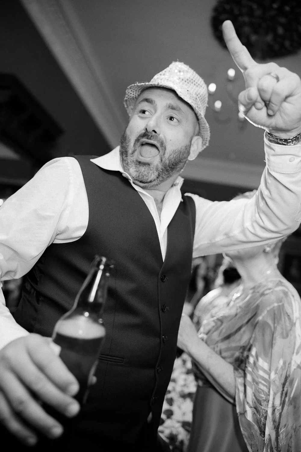 Happy wedding guest on dancefloor with hat
