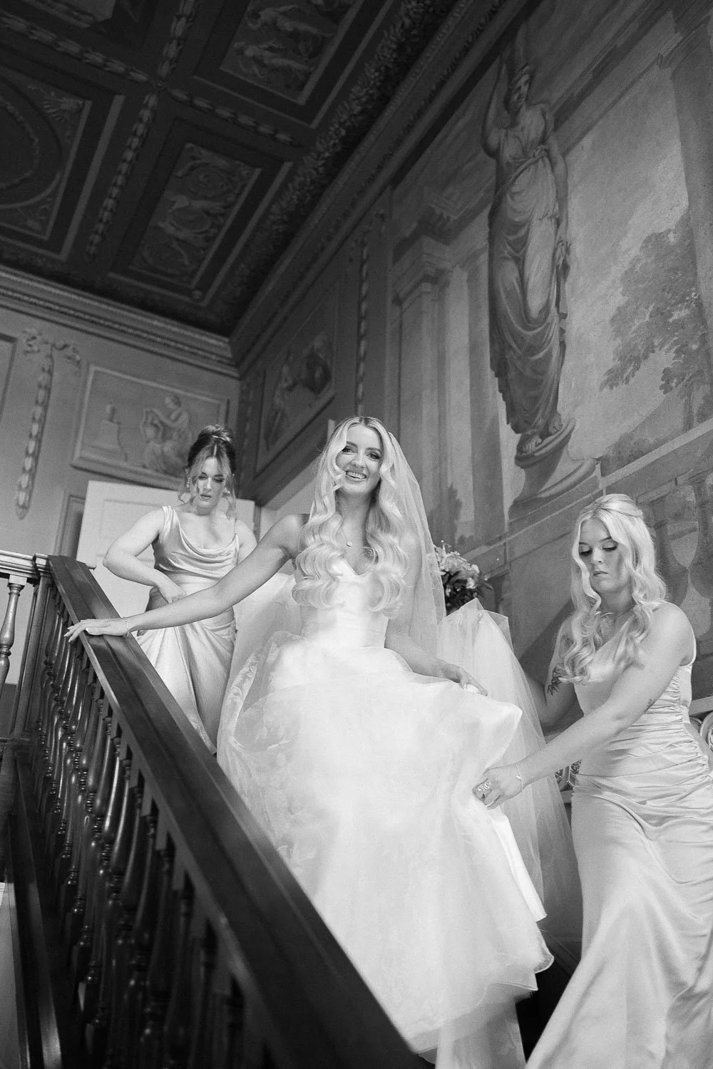 Bride and bridesmaids walking down staircase in black and white