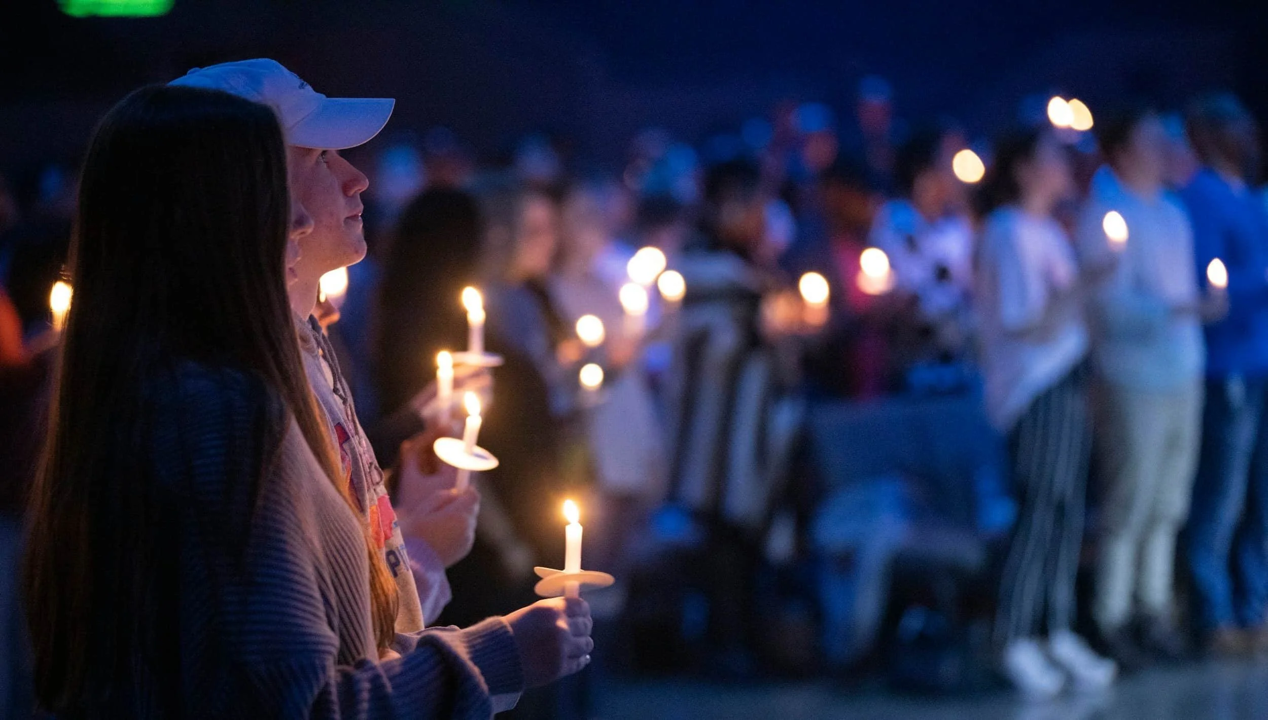 A nighttime candle light vigil symbolizing collective grief
